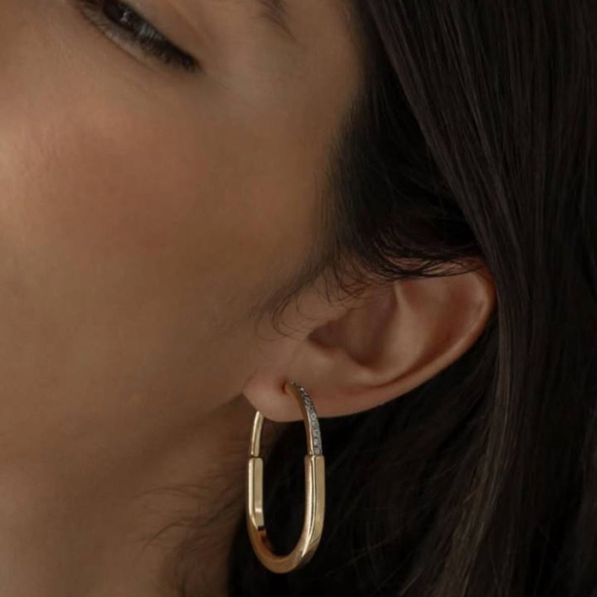 Close-up of a woman wearing the Joana Earring — a gold and rhodium mixed metal hoop with zircon detail.