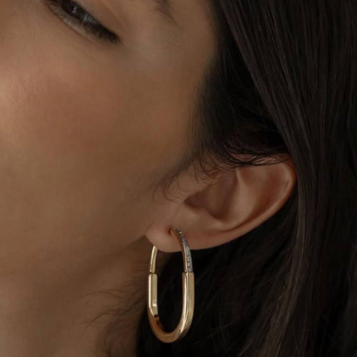 Close-up of a woman wearing the Joana Earring — a gold and rhodium mixed metal hoop with zircon detail.
